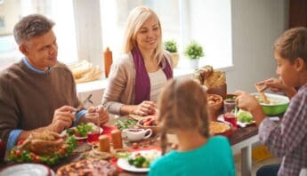 Family enjoying healthy meal together at home for wellness and nutrition concepts, representing balanced diet and family health | smiling family sharing a nutritious meal at a bright dining table for health and wellness topics | a family gathered around a table with nutritious food, emphasizing healthy eating habits and family health, in a well-lit kitchen with natural sunlight | relevance.