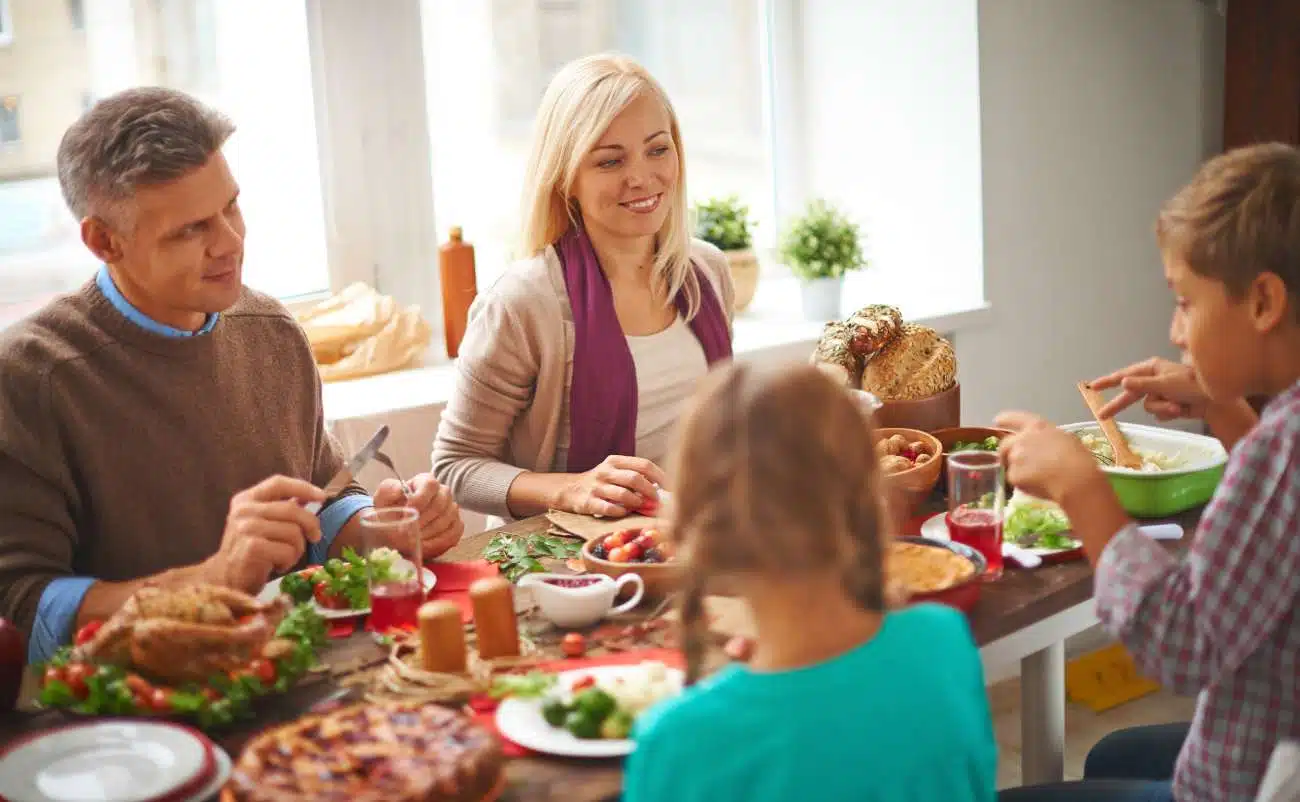 Family enjoying healthy meal together at home for wellness and nutrition concepts, representing balanced diet and family health | smiling family sharing a nutritious meal at a bright dining table for health and wellness topics | a family gathered around a table with nutritious food, emphasizing healthy eating habits and family health, in a well-lit kitchen with natural sunlight | relevance.