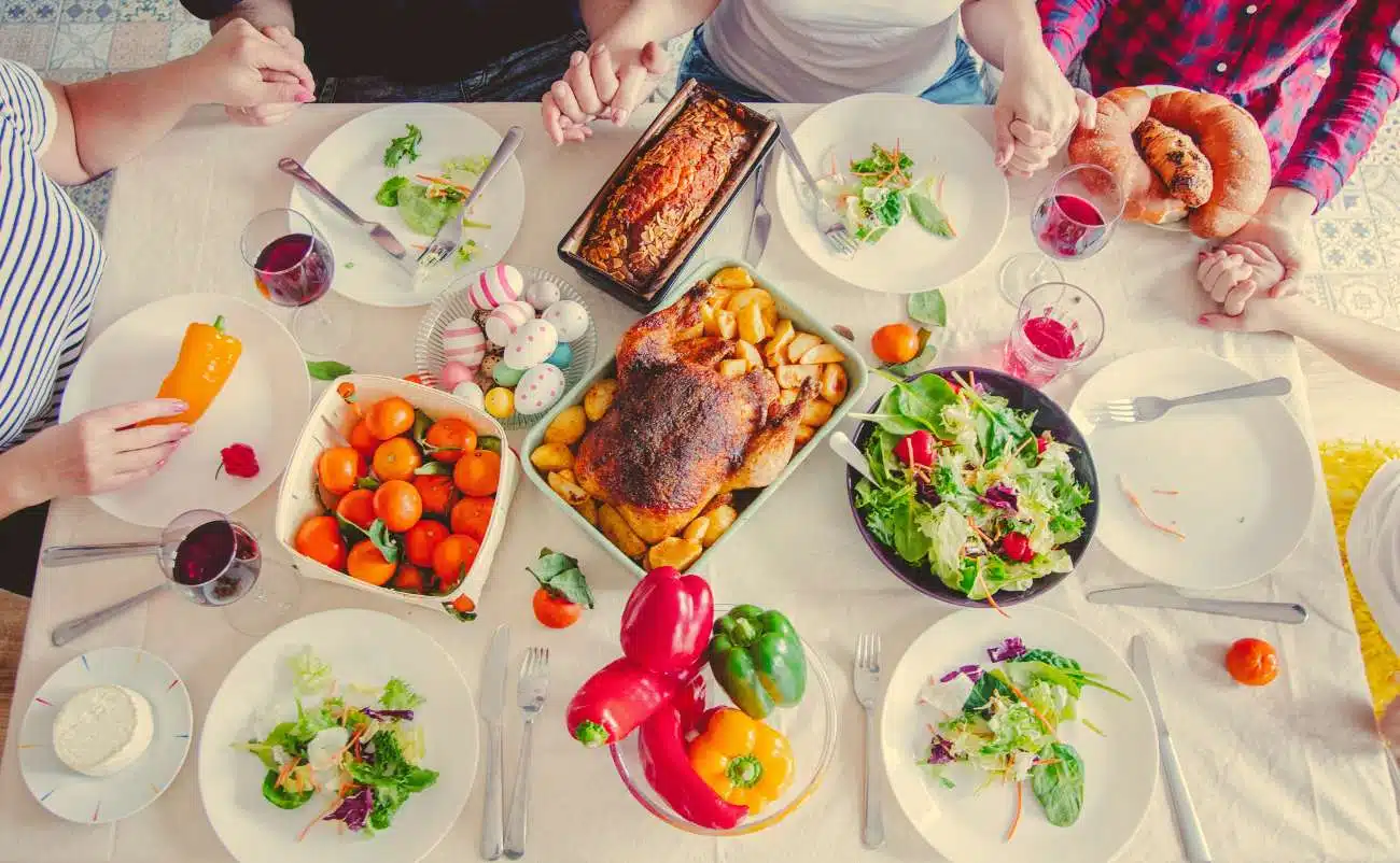 Healthy family dinner with fresh vegetables, salads, roasted meat, and drinks for balanced nutrition and wellness.