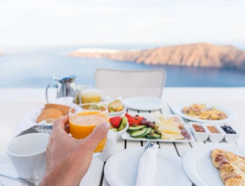 Fresh breakfast with juice, fruits, pizza, and coffee overlooking a scenic landscape, promoting healthy lifestyle and balanced diet.