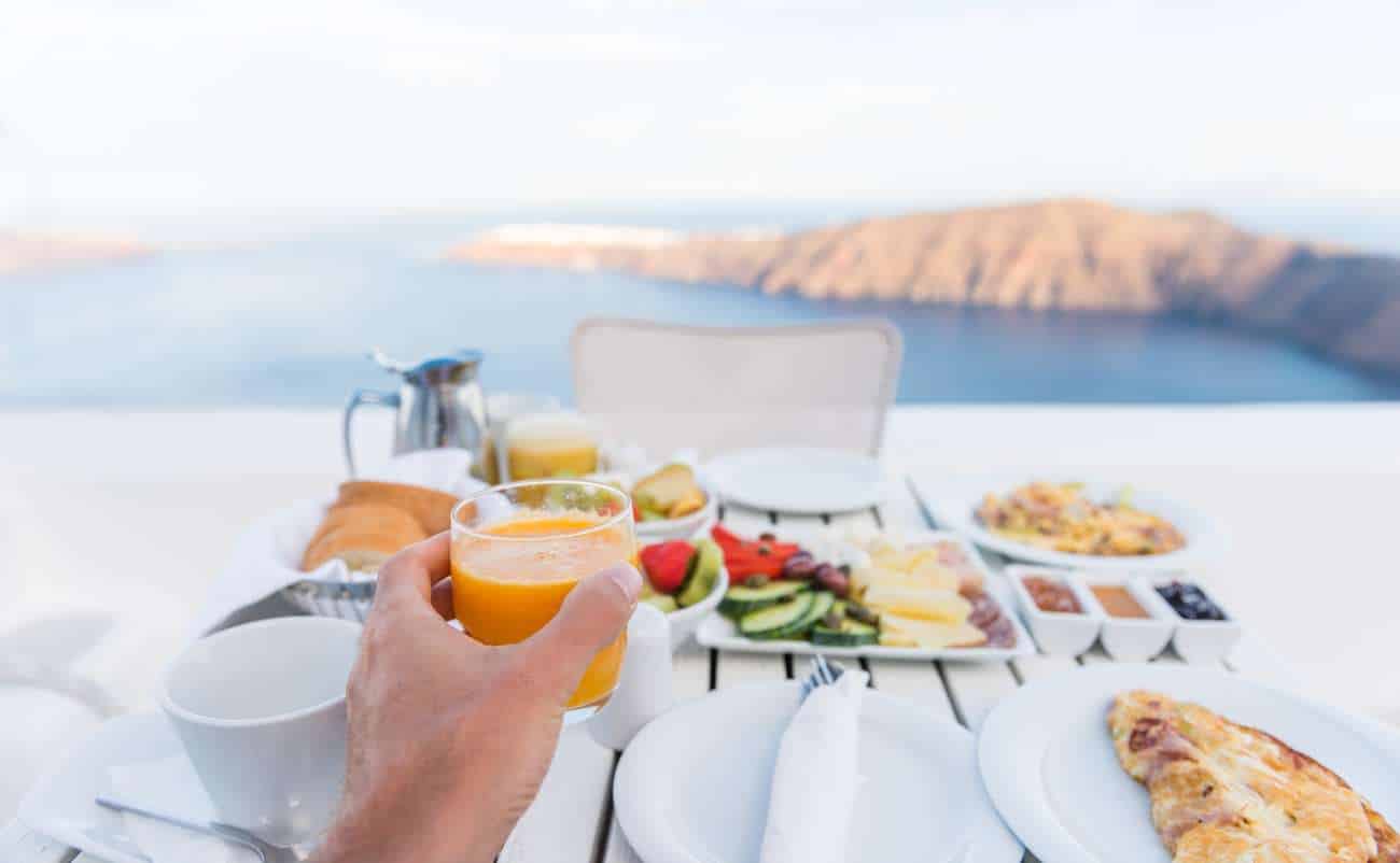 Wake Up to Flavor: 10 Delicious Mediterranean Breakfast Ideas to Energize Your Mornings 1 Fresh breakfast with juice, fruits, pizza, and coffee overlooking a scenic landscape, promoting healthy lifestyle and balanced diet.