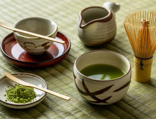 Green tea and matcha powder with traditional Japanese tea utensils on a bamboo mat, emphasizing healthy beverage choices for wellness.