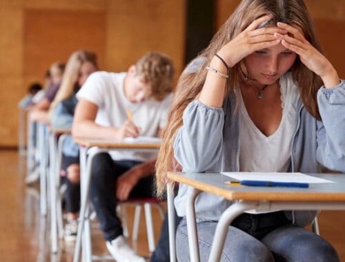 Stressful school exam scenario with focused students taking a test in classroom.