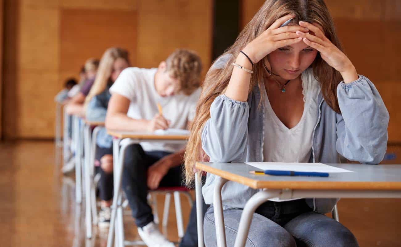 Stressful school exam scenario with focused students taking a test in classroom.