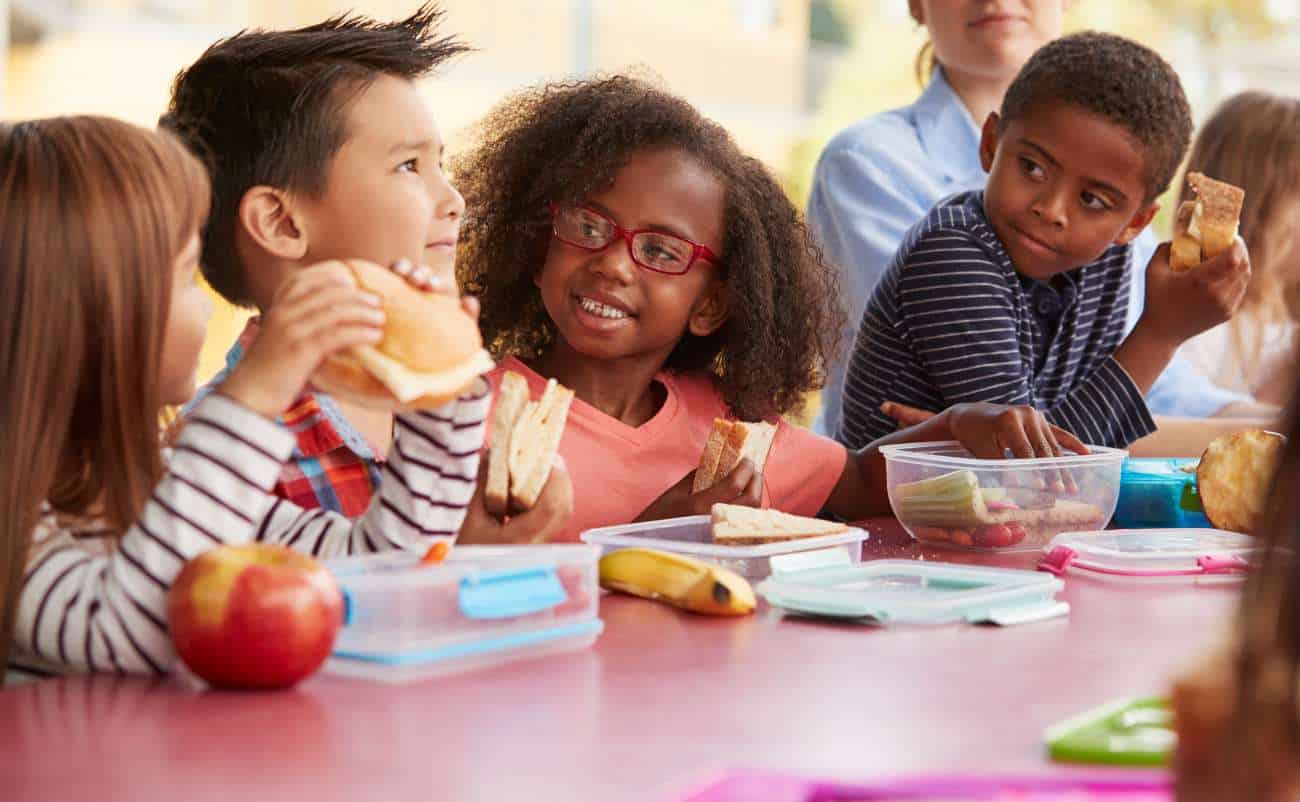 Kids school lunch eating healthy sandwiches and fruit at desk during lunch break healthy meal options for children health and wellness education for kids.