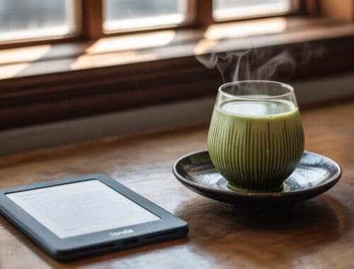 Steaming green tea in a glass cup on a wooden table with a digital e-reader nearby, set by a sunlit window, illustrating a calm and healthy lifestyle.