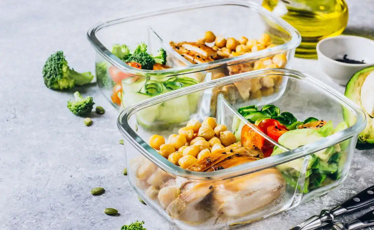 Freshly prepared healthy meal prep containers with chopped vegetables, chickpeas, and grilled chicken for balanced nutrition and weight management.