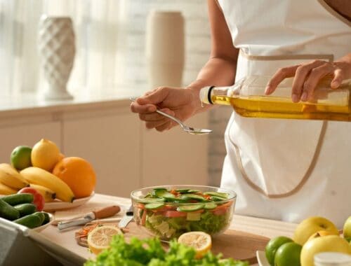 Fresh vegetable salad being prepared with olive oil in a bright kitchen.