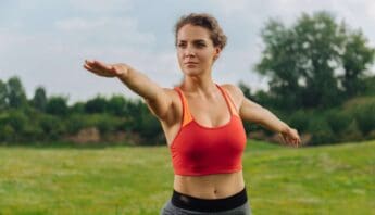 Metabolism Matters 7 Simple Hacks to Supercharge Your Energy and Burn Fat 22 Stretching outdoors woman in athletic wear doing arm stretch on green field.