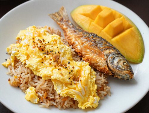 Fried fish, rice, eggs, and mango.