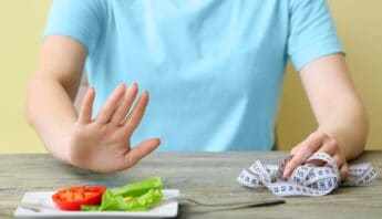 Calorie counting and healthy eating with fresh vegetables and a measuring tape on a wooden table.