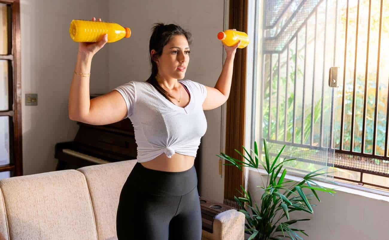 Lifting dumbbells at home for fitness and strength training, woman exercising indoors with natural sunlight, healthy lifestyle, female workout, indoor fitness routine, wellness, and physical activity.