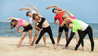 Stretching yoga group on the beach for flexibility and fitness.