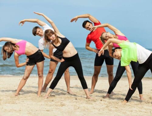 Stretching yoga group on the beach for flexibility and fitness.