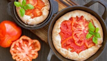Fresh homemade tomato pizza with basil, served in cast iron skillets on a wooden surface, emphasizing healthy and delicious meal options.