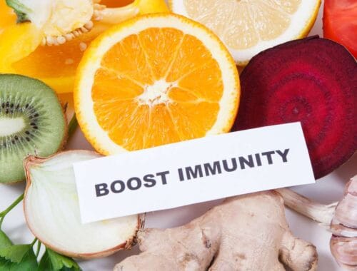 Fresh fruits like oranges, kiwi, ginger, and garlic, with a "Boost Immunity" sign, promoting healthy eating habits for better immune function and overall wellness.