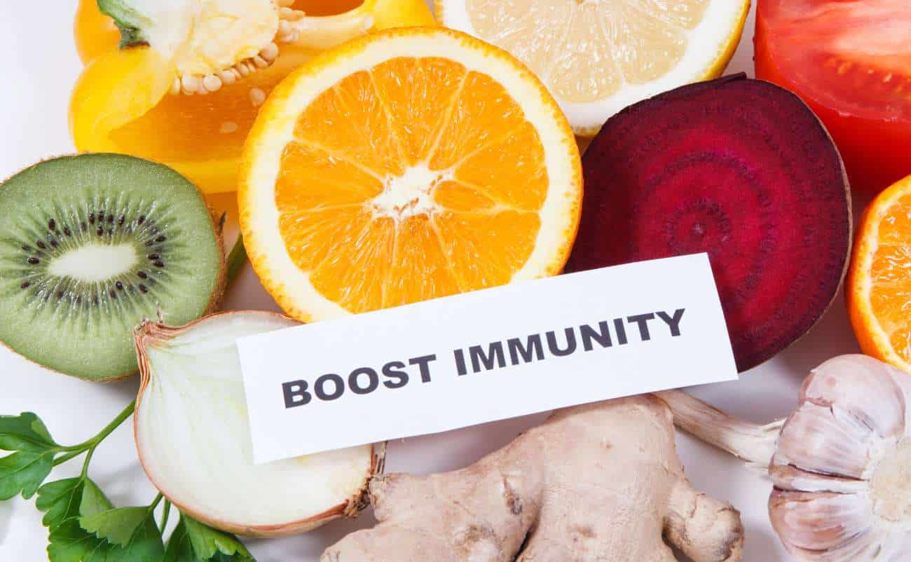 Fresh fruits like oranges, kiwi, ginger, and garlic, with a "Boost Immunity" sign, promoting healthy eating habits for better immune function and overall wellness.