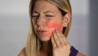 Blonde woman experiencing tooth pain, touching her cheek with a pained expression, highlighting dental discomfort and oral health issues.