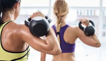 Dumbbell shoulder workout women lifting weights at fitness class.