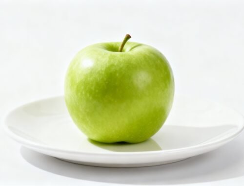 Fresh green apple on a white plate, symbolizing healthy eating and nutrition.