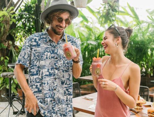 Refreshing tropical smoothies enjoyed by a smiling man and woman in a lush outdoor setting. Perfect for health-conscious eating and tropical drinks.