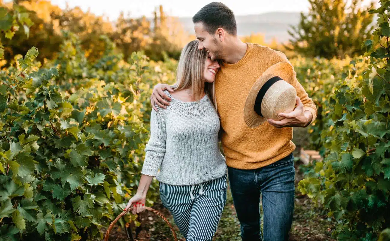 Joyful couple hugging in vineyard during autumn, healthy lifestyle, wellness, outdoor activity, romance, leisure, fall scenery, natural environment, smiling, affection, companionship, healthy living.