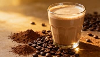 Protein Coffee Drink Recipe Energizing Brew With a Protein Boost 13 Rich coffee beverage in a clear glass surrounded by coffee beans and cocoa powder, highlighting a tasty and energizing drink option.