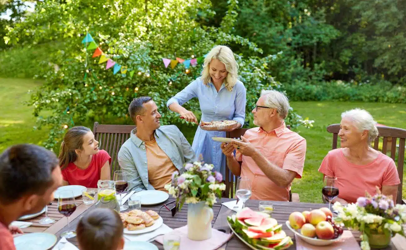 Freshly prepared birthday cake being served at outdoor family gathering with colorful decorations and healthy food options.