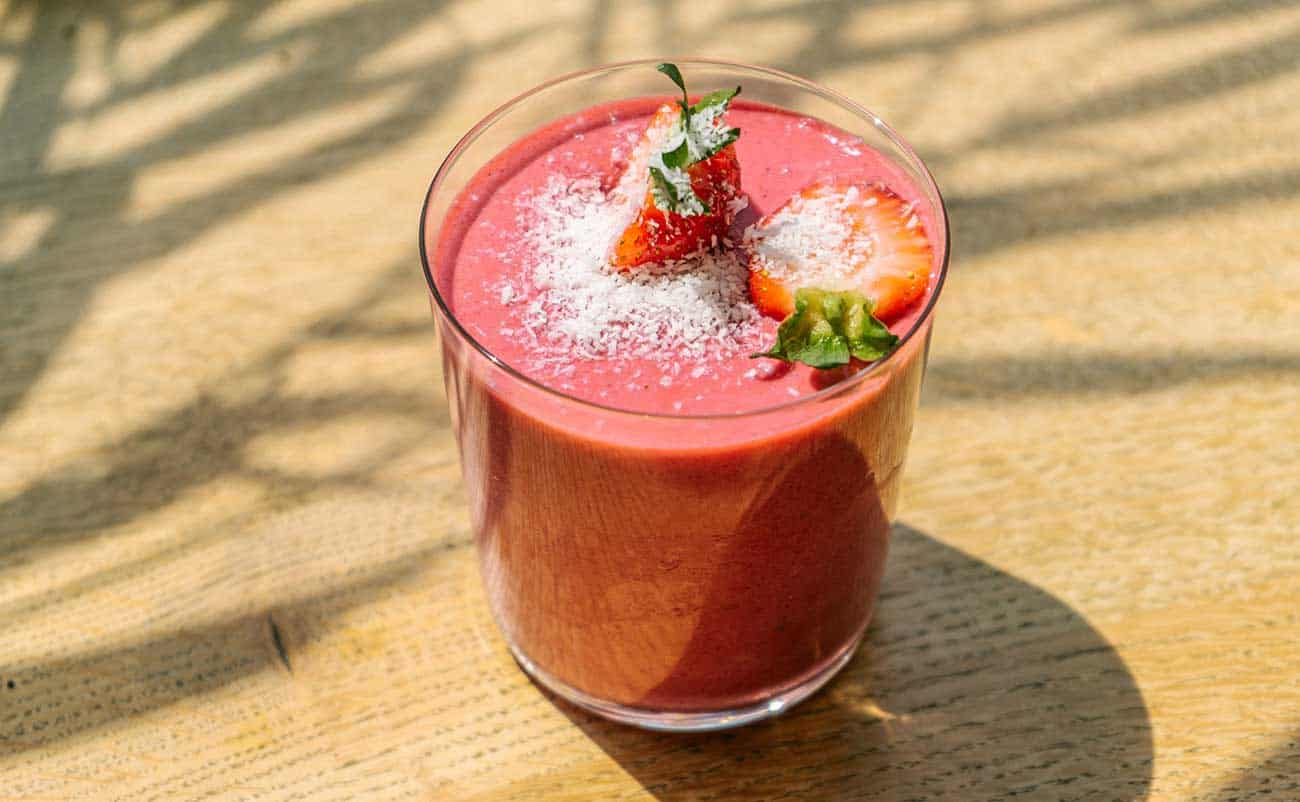 glass full of strawberry smoothie on table