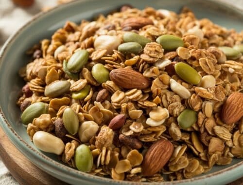 Mixed homemade granola with almonds, pumpkin seeds, and dried fruit on a rustic plate, ideal for healthy snacking or breakfast options.