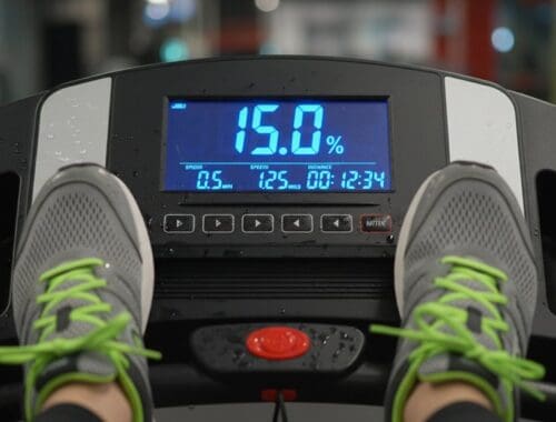 An image of a treadmill display showing fat percentage at 15%, with feet in athletic shoes, indicating a workout in progress.