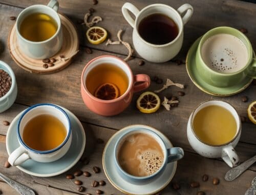 Rich assortment of herbal teas and coffee cups on rustic wooden table, surrounded by lemon slices, coffee beans, and tea infusers, showcasing healthy beverage options.