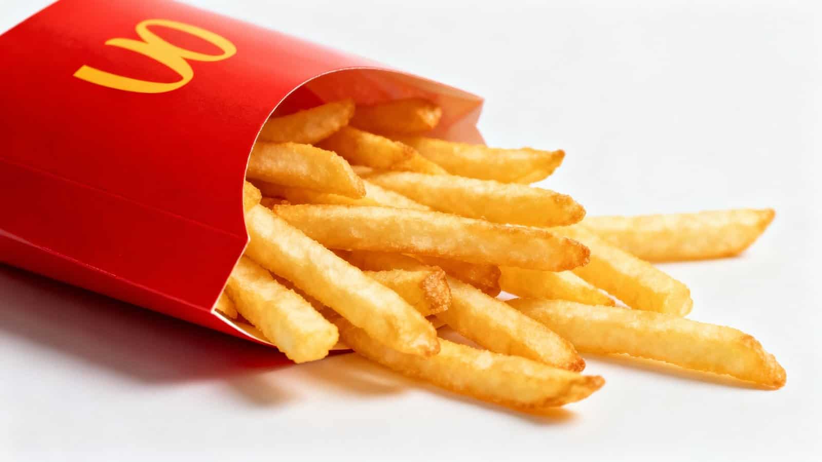 Delicious, crispy French fries spilling out of a red fast-food container, perfect for snacks or meals, emphasizing fast food and casual dining.