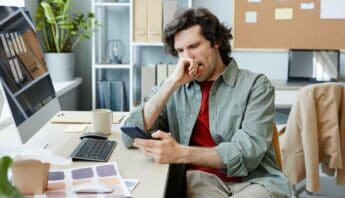 Beat Procrastination: 9 Proven Strategies to Unlock Your Productivity 46 Feeling unwell man coughing at office desk looking at smartphone health and wellness concerns healthcare stress support concept.