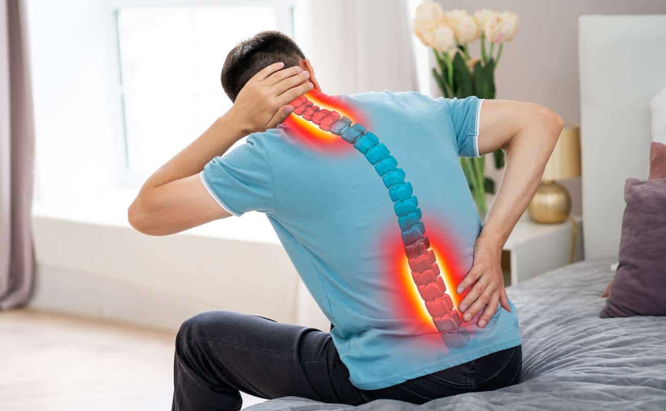 Neck and lower back pain relief caused by spinal issues, with a digital illustration of a spine overlay on a man experiencing discomfort in a bedroom.