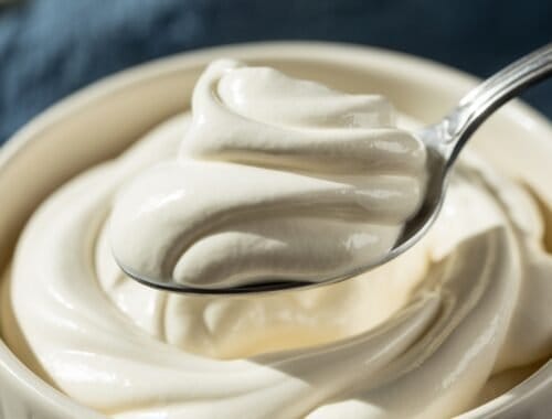 Creamy yogurt or sour cream in a bowl with a spoon, close-up shot.