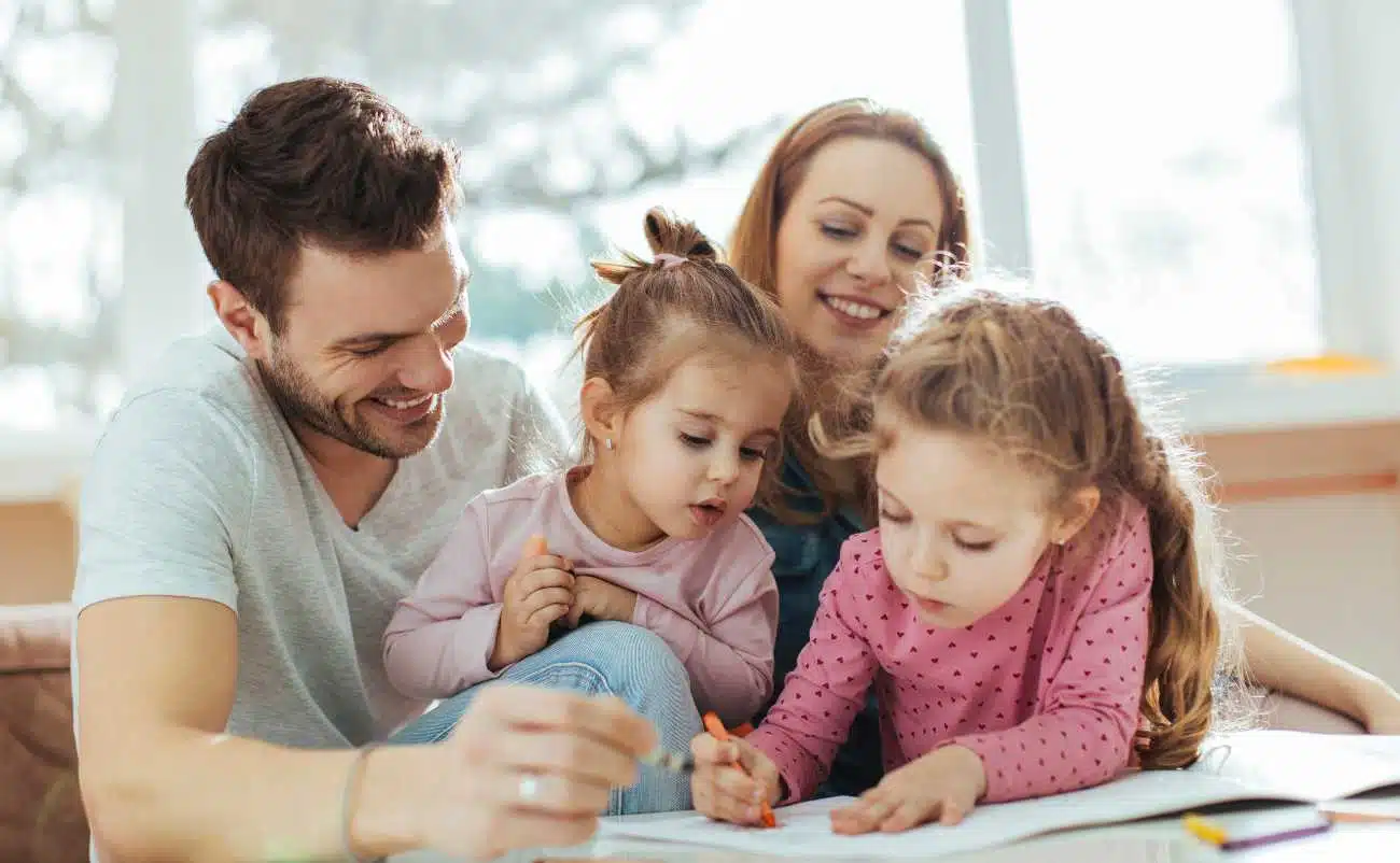 Family spending quality time together at home, children drawing with parents, indoor activity promoting family health and wellness, happy family bonding.