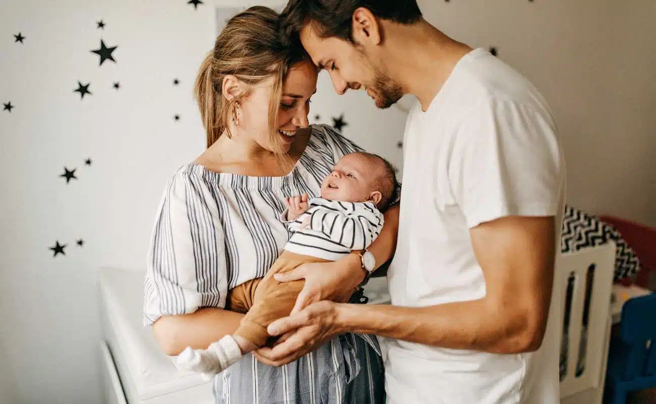 A happy family holding a newborn baby indoors, celebrating new life and bonding moments, emphasizing health, love, and family wellness.