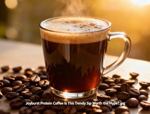 Coffee beverage with foam in glass mug surrounded by coffee beans on wooden surface at sunset.