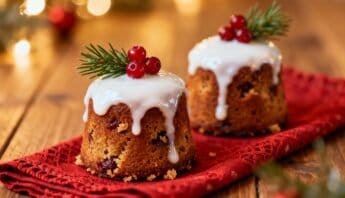 Delicious mini Christmas cakes topped with white icing, red berries, and pine sprigs on a red cloth, evoking holiday warmth and seasonal celebration.