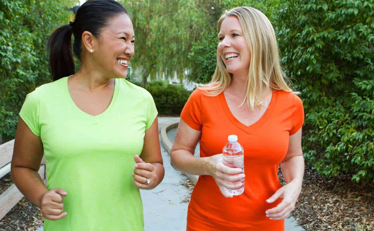 women doing walking exercises in the park with water bottle