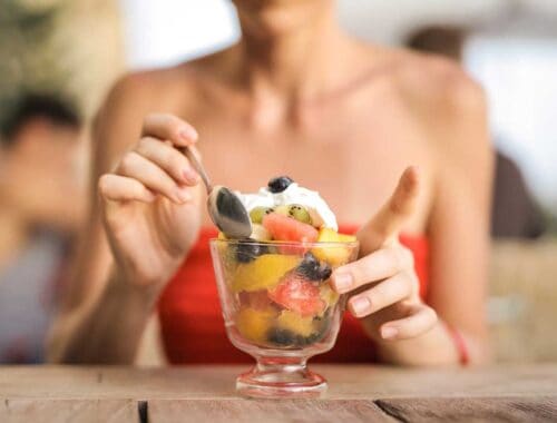 Fresh fruit salad with whipped cream in a glass bowl, healthy dessert option for balanced nutrition.